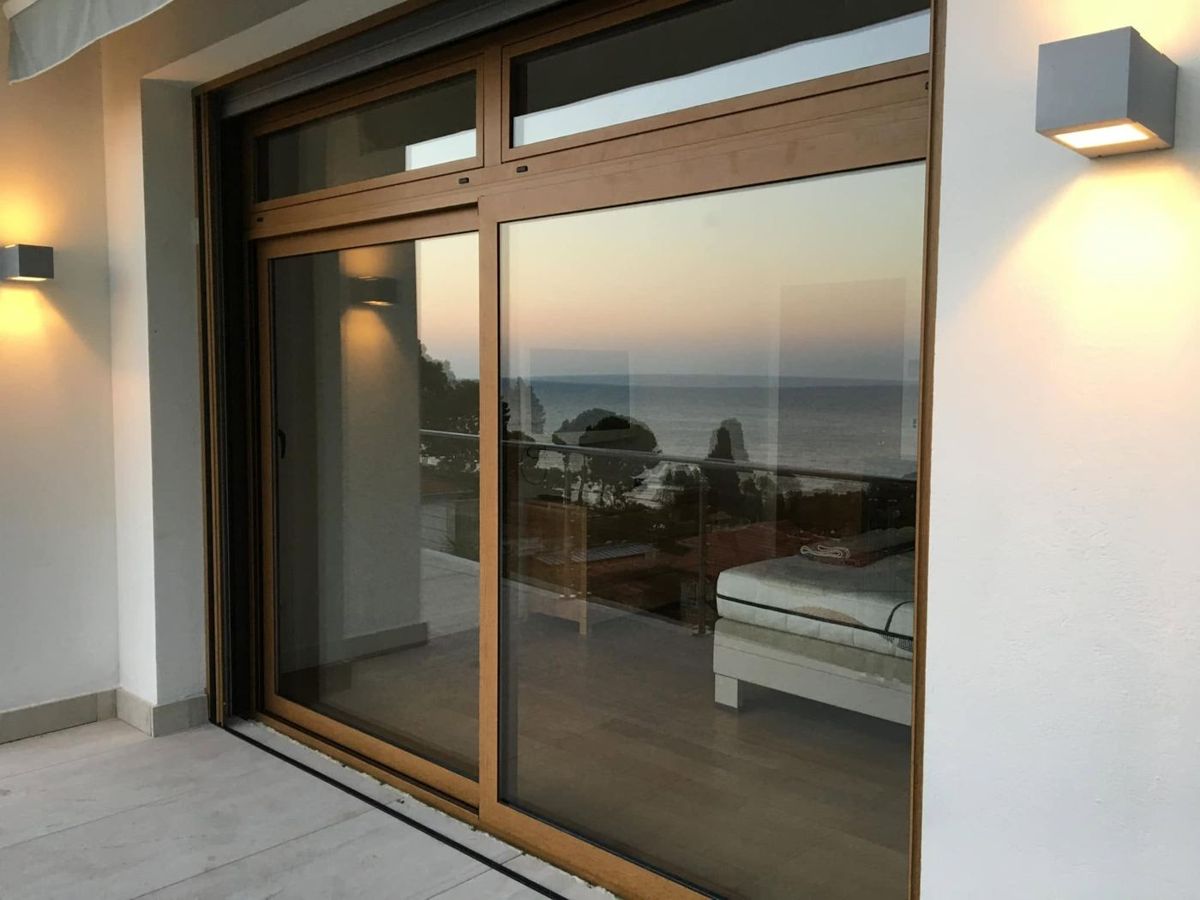 Portafinestra scorrevole effetto legno con vista sul mare al tramonto